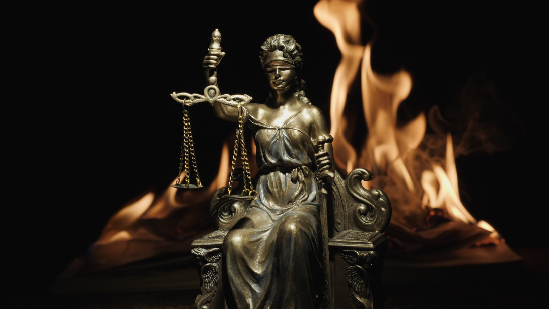 Statue of Lady Justice on the background of the flame of a burning book. ©Dmytro Diedov on iStockPhoto